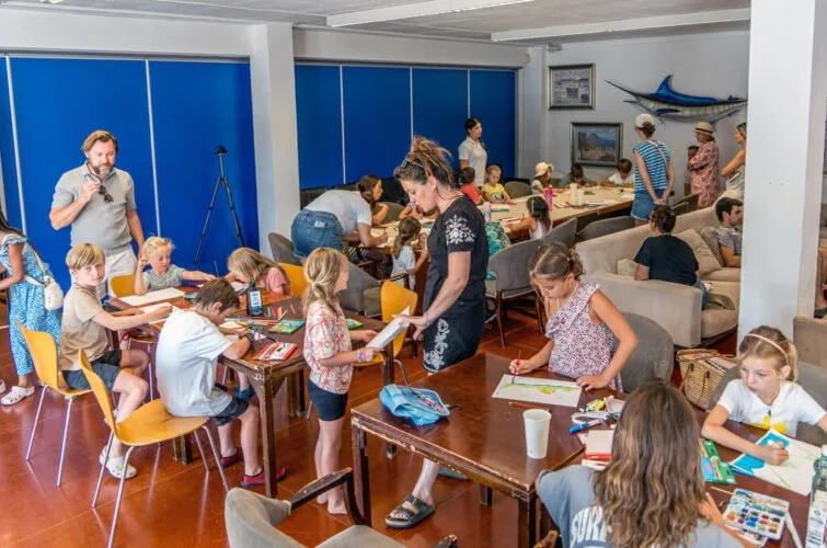 Niños participando en una actividad artística y educativa en un lugar con decoración marina.
