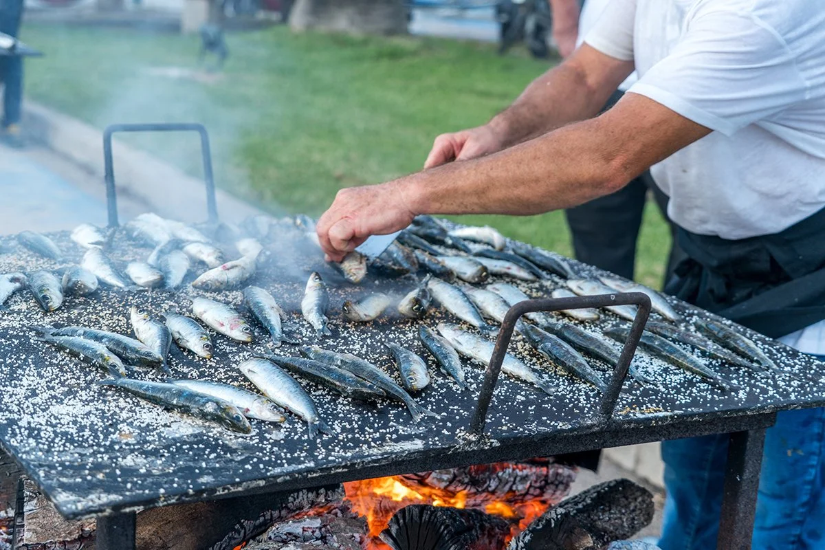 Persona cocinando sardinas en una parrilla al aire libre