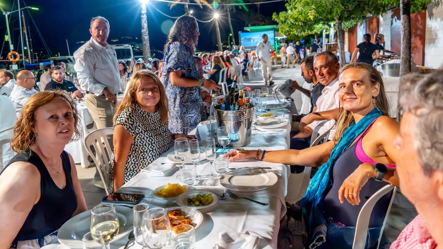 Grupo de personas sentadas en una mesa en un restaurante al aire libre durante la noche