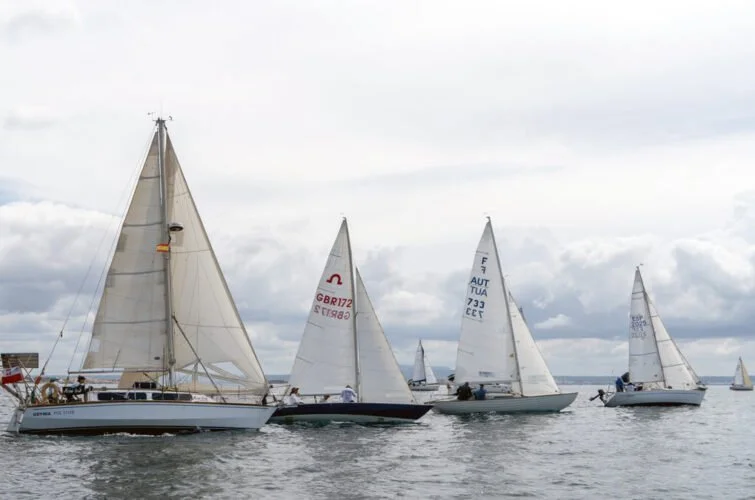Varias embarcaciones de vela navegando en el mar bajo un cielo nublado.