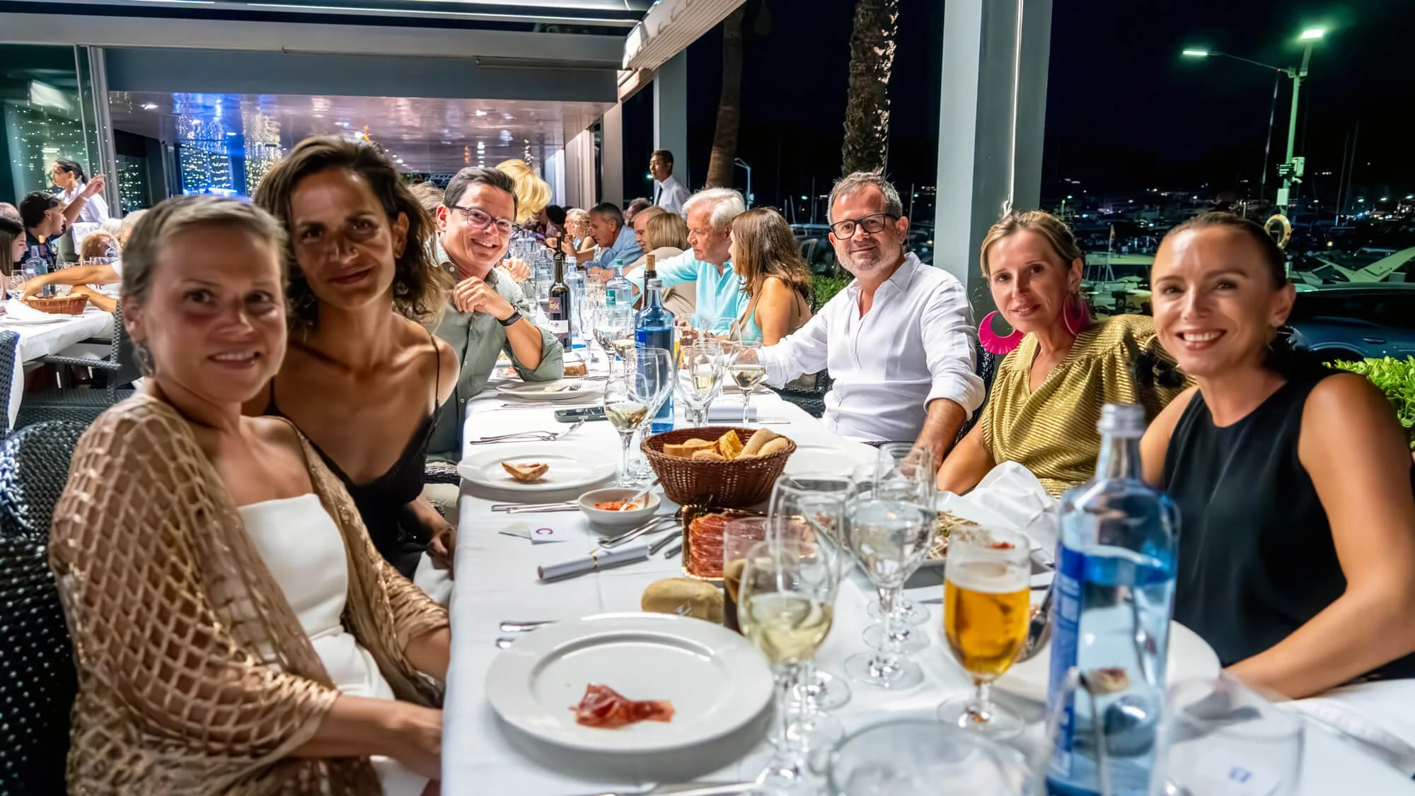 Grupo de personas disfrutando de una cena en un restaurante al aire libre por la noche.