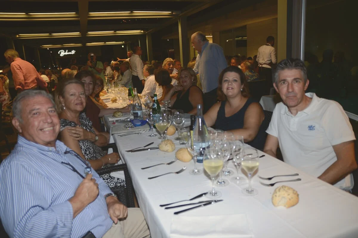 Grupo de personas cenando en un restaurante elegante, con mesas decoradas y comida servida.
