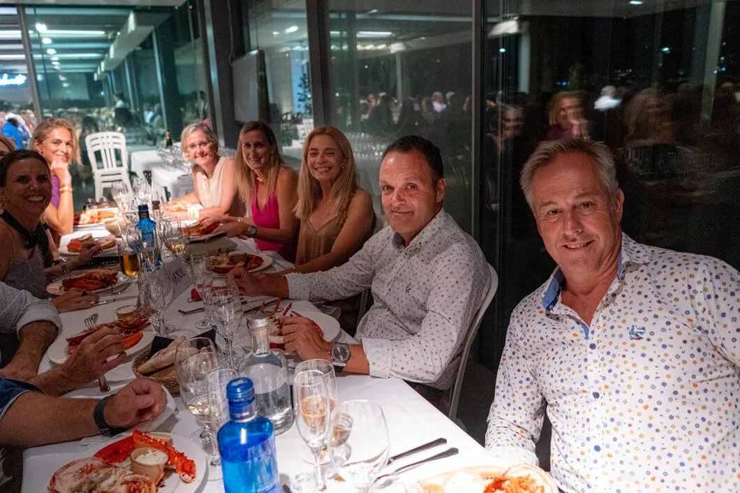 Grupo de personas comiendo en una cena social en un restaurante elegante con vista a un área luminosa y moderna.