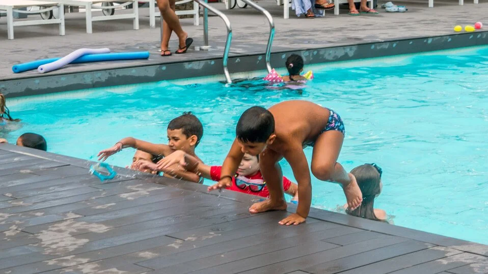Niños en la piscina jugando y chapoteando.