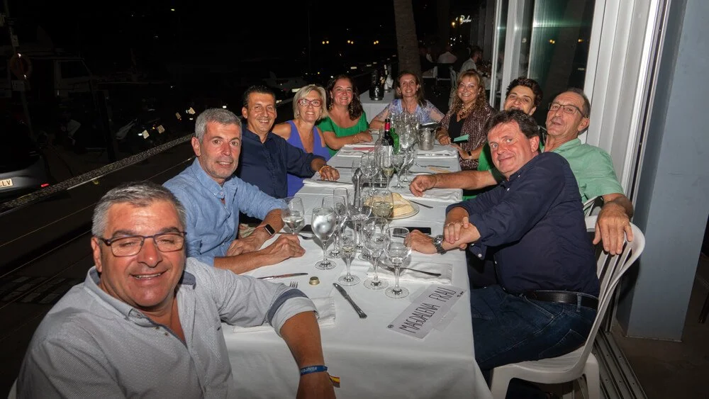 Grupo de personas sentadas en una mesa en un restaurante, celebrando con comida y bebidas, durante la noche.