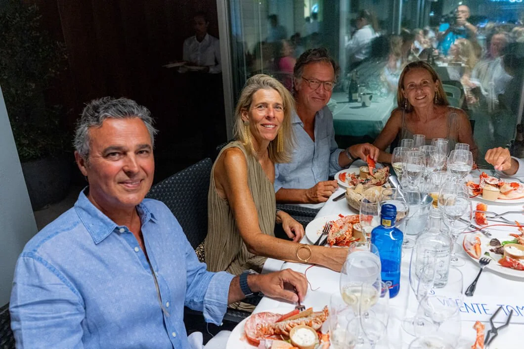 Cuatro personas sentadas en una mesa en un restaurante, disfrutando de una comida que incluye mariscos y bebidas.