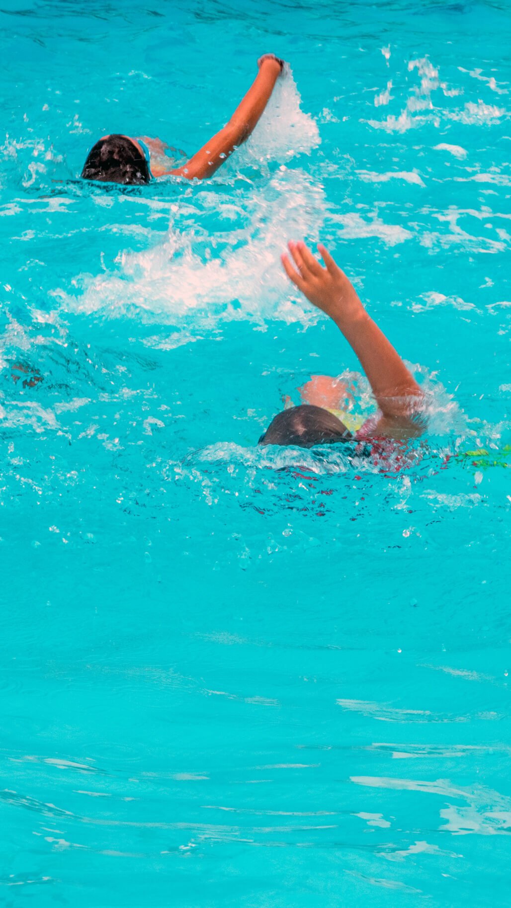 Dos niños nadando en una piscina y dándose la mano.