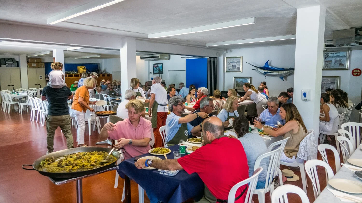 Personas comiendo en un restaurante con decoraciones marinas y muchos comensales