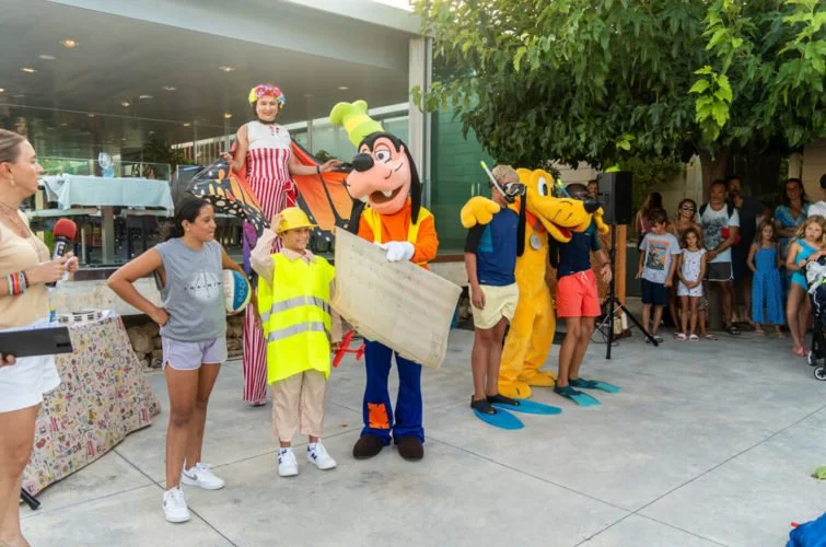 Niños y personajes de Disney, como Goofy, en un evento infantil al aire libre.