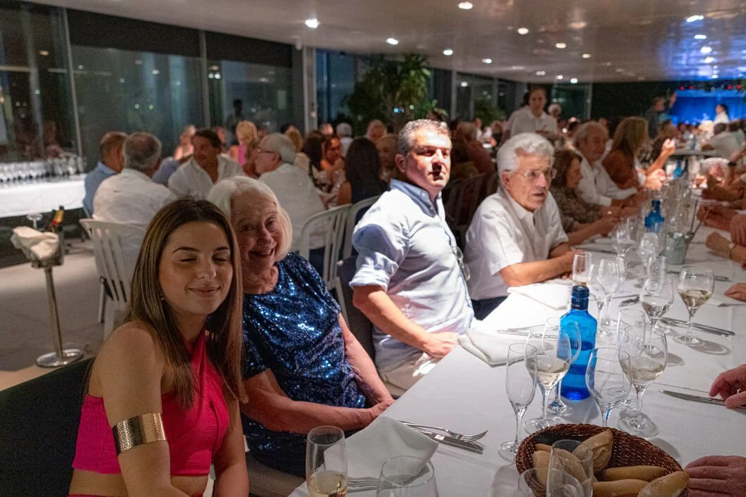 Personas cenando en un restaurante elegante con muchas mesas y copas de vino.