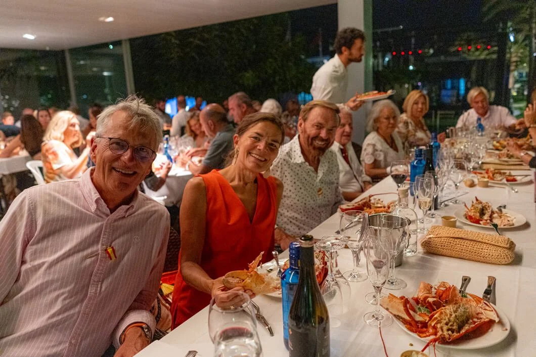 Grupo de personas en una cena formal en un restaurante, disfrutando la comida y la compañía.