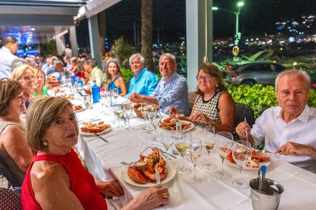 Grupo de personas cenando en un restaurante durante la noche, con comida y bebidas en la mesa.