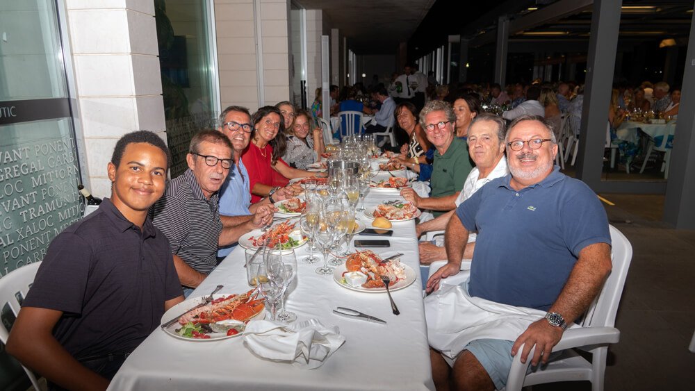 Grupo de personas sentado en una mesa larga en un restaurante con comida de mariscos en la mesa, celebrando una reunión o celebración.