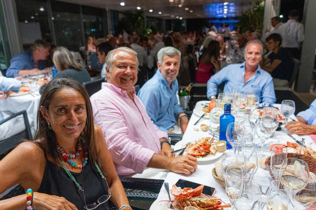 Personas sentadas en una mesa, celebrando con comida y bebida en un restaurante elegante por la noche.