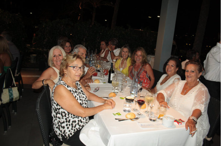 Grupo de mujeres sentadas en una mesa en un restaurante durante la noche, disfrutando de comida y bebida.
