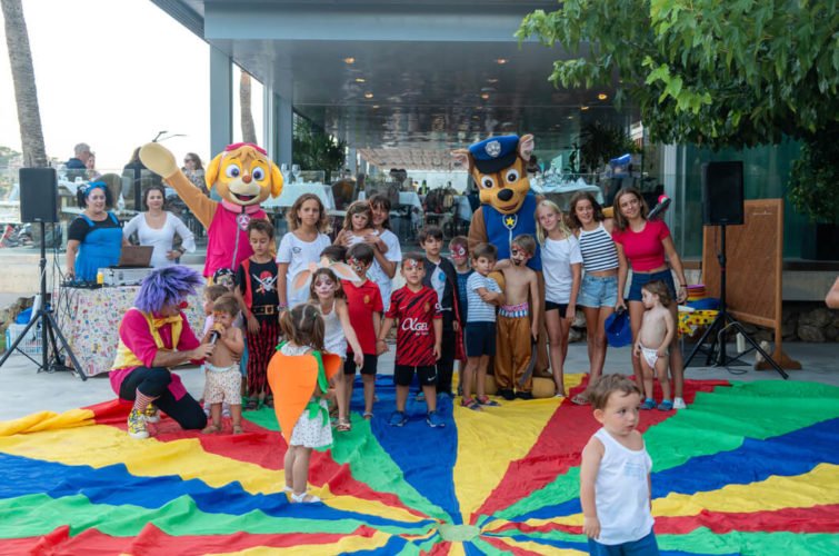 Niños en una fiesta infantil con personajes de cartoon y un piso de colores