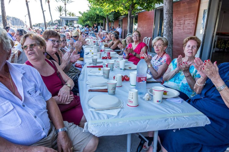 Un grupo de personas mayores sentadas en una mesa al aire libre disfrutando de una comida o celebración