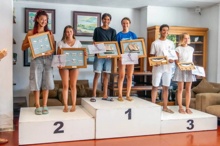 Niños en un podio de premiación, con certificados y premios en mano, en una ceremonia de reconocimiento.