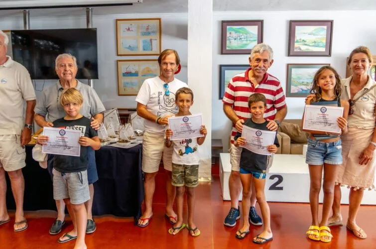 Grupo de niños y adultos en una ceremonia de premiación, con diplomas en mano y fondo con cuadros decorativos en una sala.