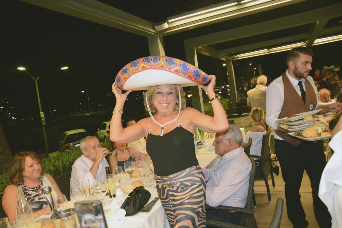 Mujer sonriendo con sombrero mexicano en celebración en restaurante.