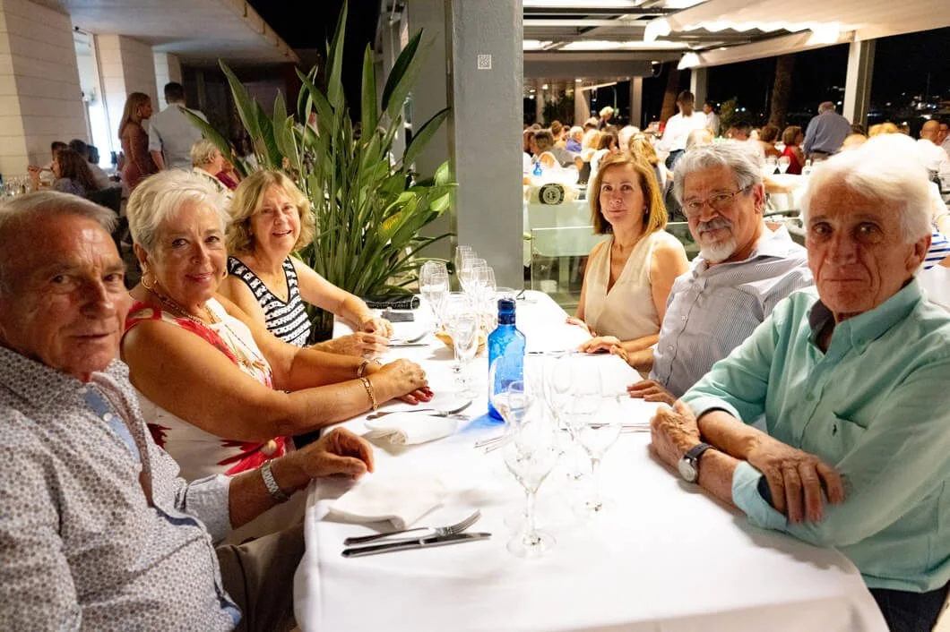 Personas mayores sentadas en una mesa elegante en un restaurante, lista para cenar.