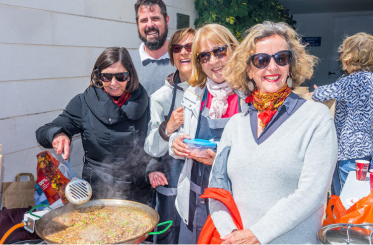 Grupo de personas mayores cocinando y sonriendo en una parrilla al aire libre