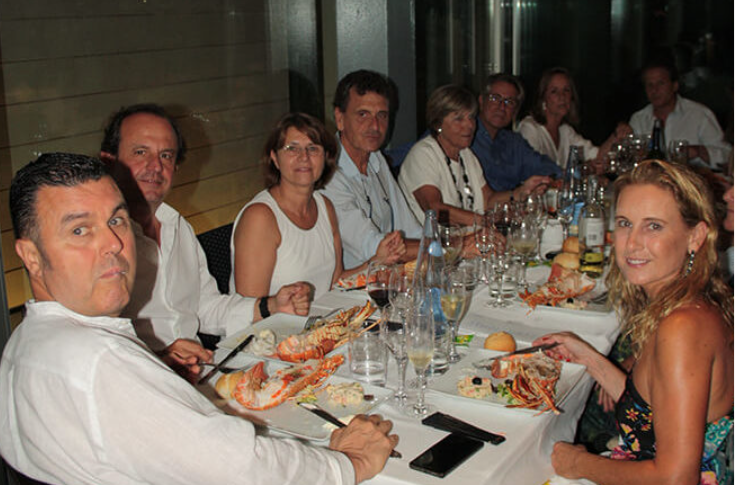 Grupo de personas sentadas en una mesa en una comida elegante en un restaurante.