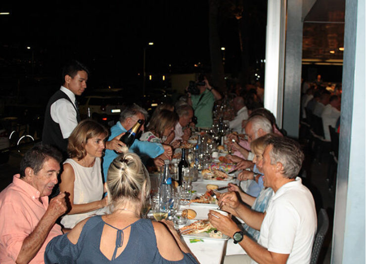 Grupo de personas cenando en un restaurante elegante, con comida y bebidas sobre la mesa.