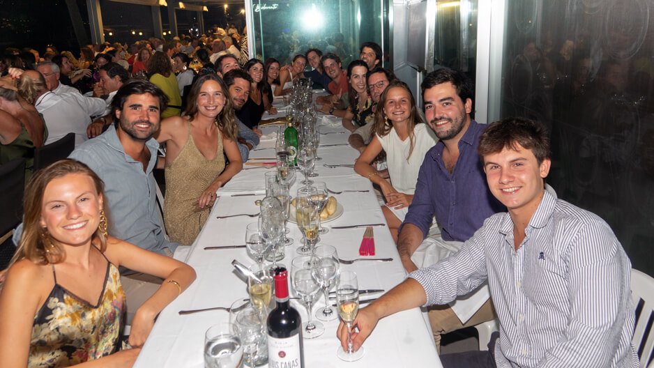 Grupo de personas sonriendo y brindando en una cena en un restaurante elegante.