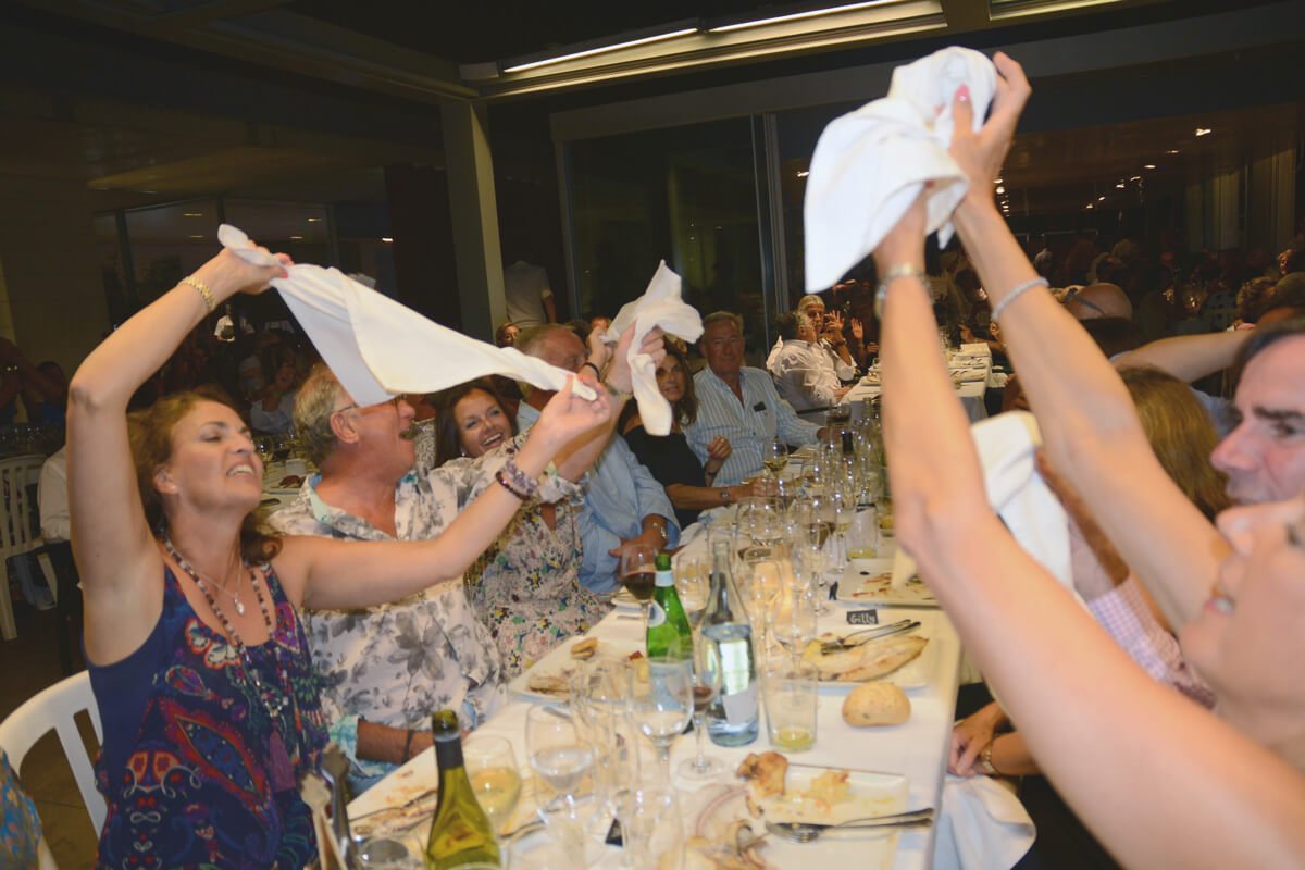 Personas en una cena arrojándose servilletas en un ambiente de celebración.