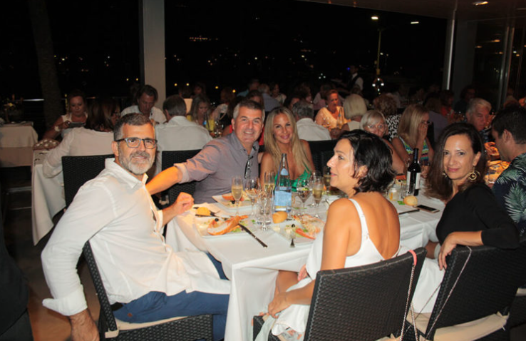 Grupo de personas en una cena en un restaurante elegante por la noche, disfrutando y sonriendo.