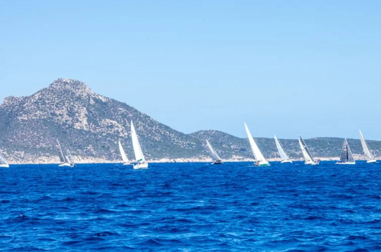 Vela en el mar con montañas al fondo