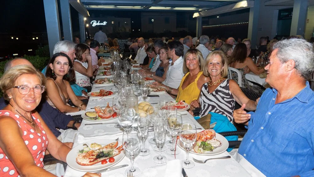 Grupo de personas disfrutando de una comida formal en un restaurante durante la noche.