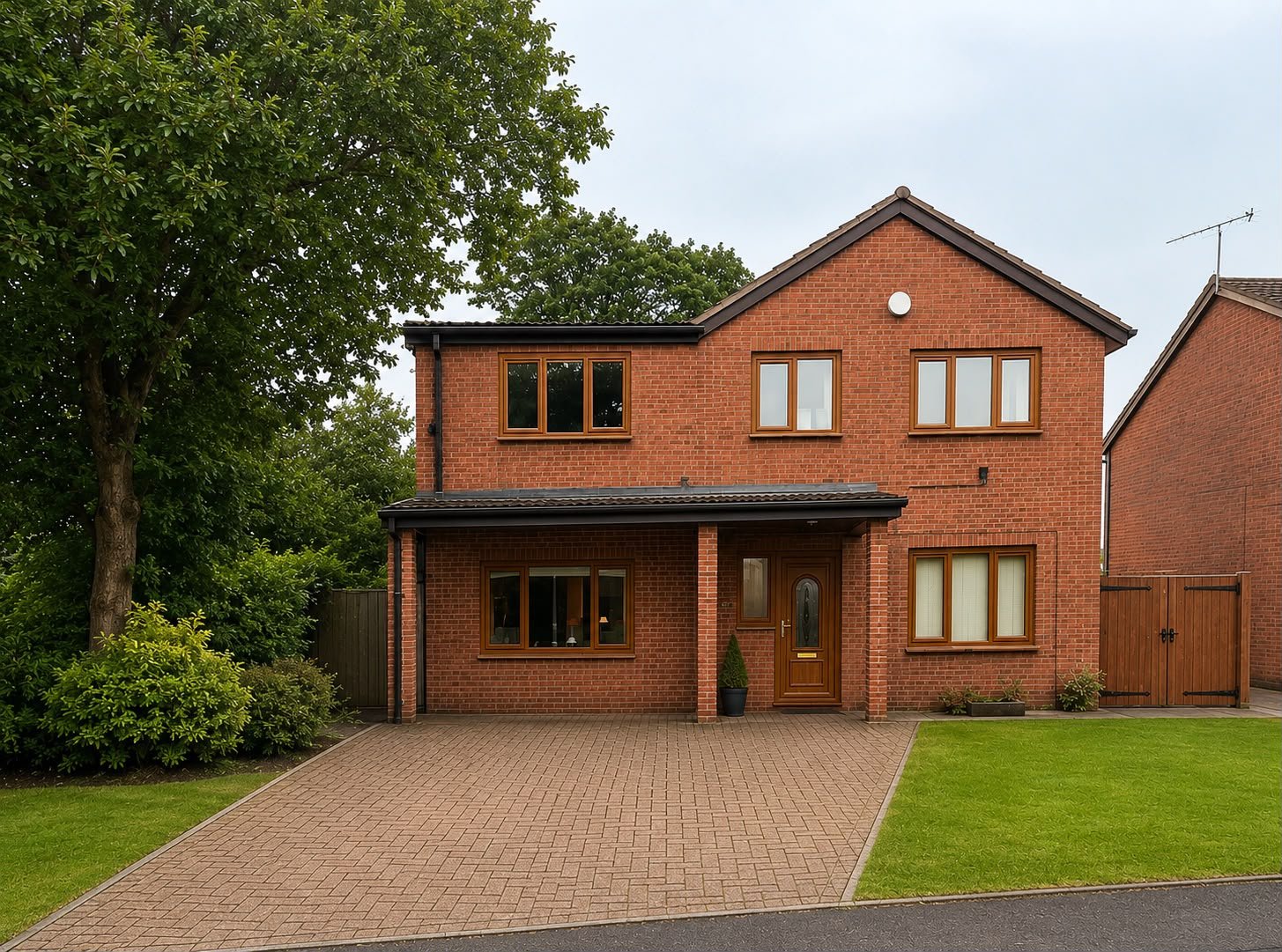 A modern, two-story brick house with a brown front door, multiple rectangular windows, and a driveway leading up to the entrance, surrounded by a well-maintained lawn and some trees.
