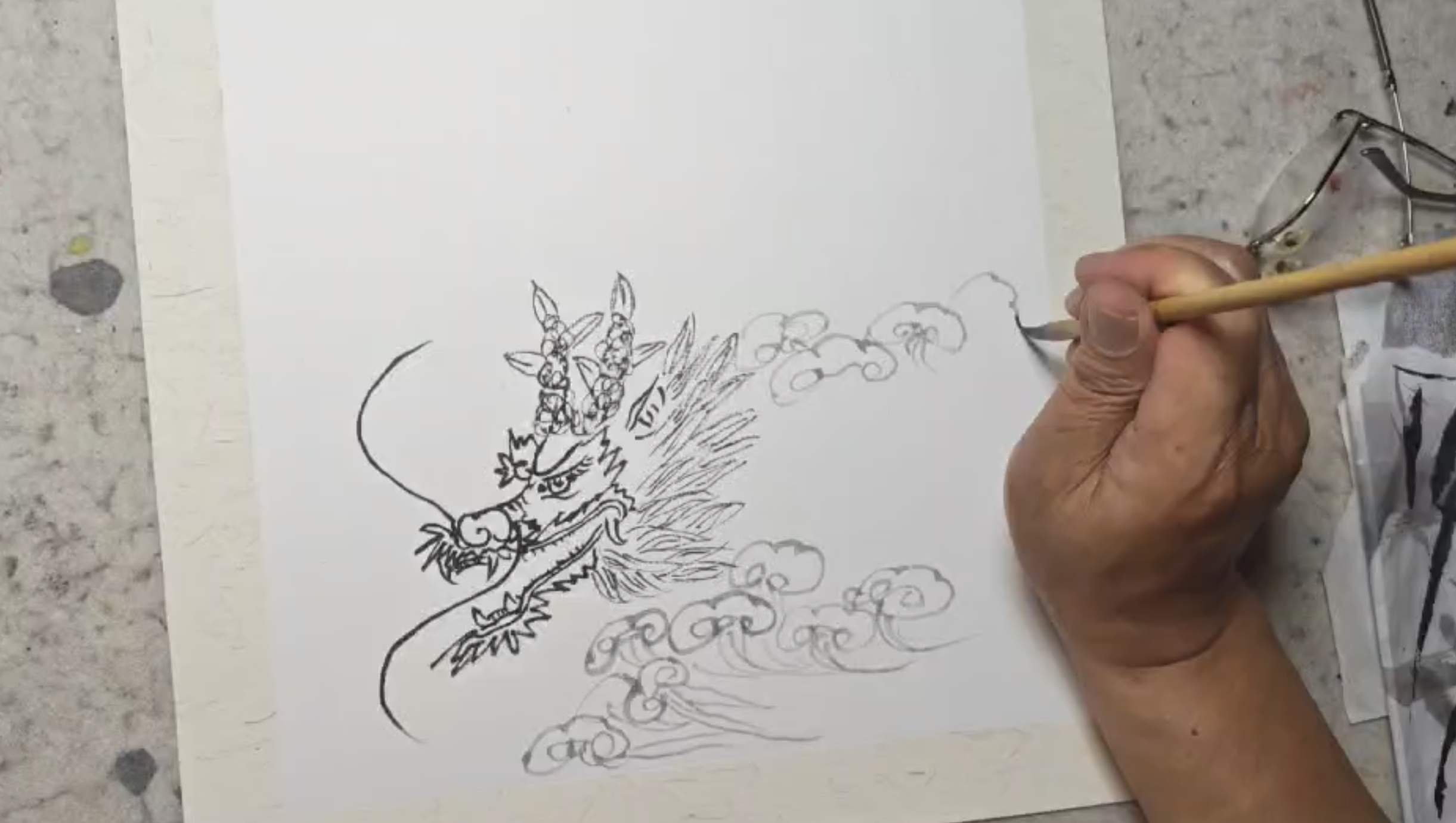 Artist sketching a traditional Chinese dragon before creating an East Asian brush painting.
