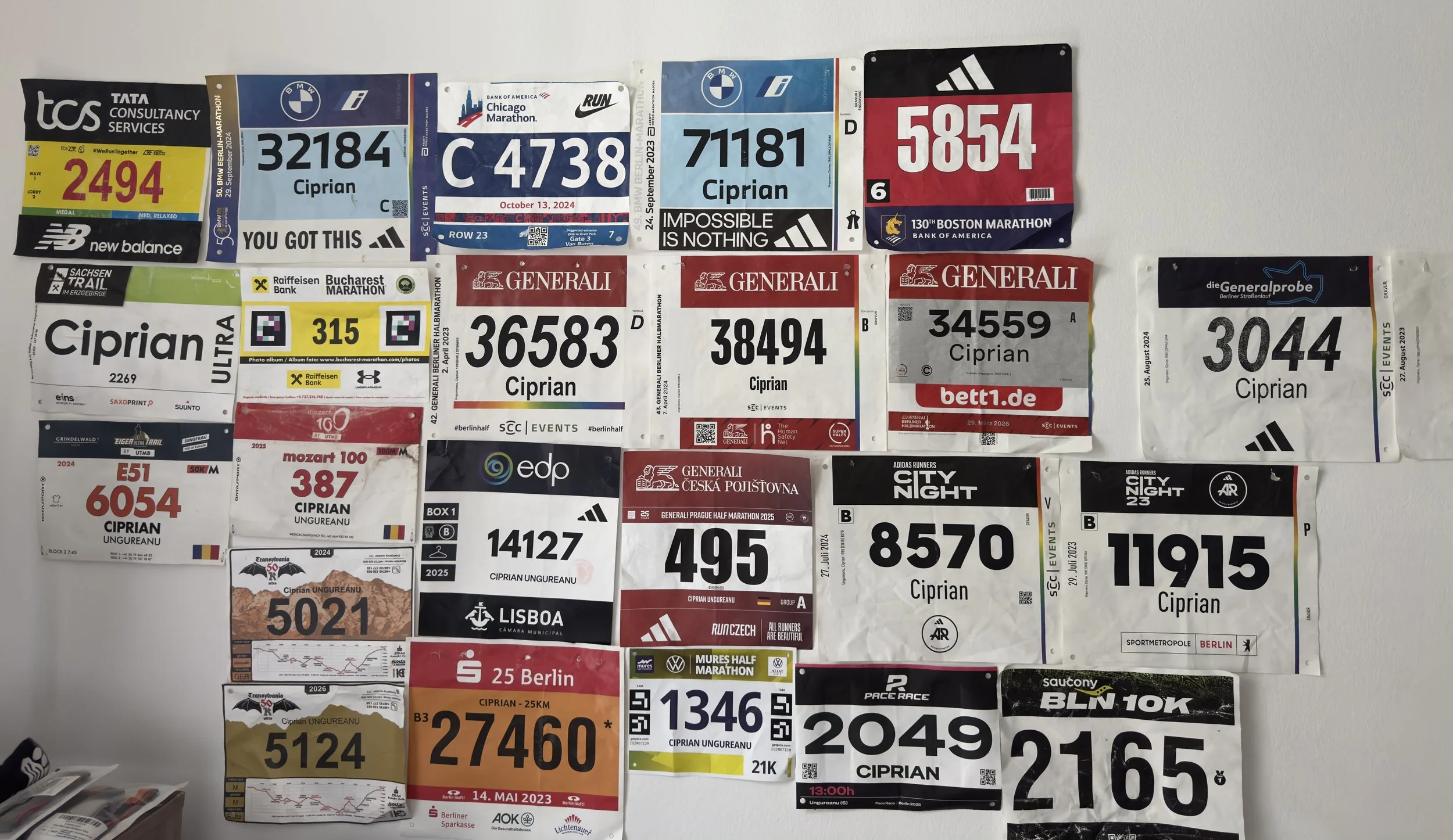 A wall with numerous road and trail race bibs attached, all belonging to Ciprian Ungureanu