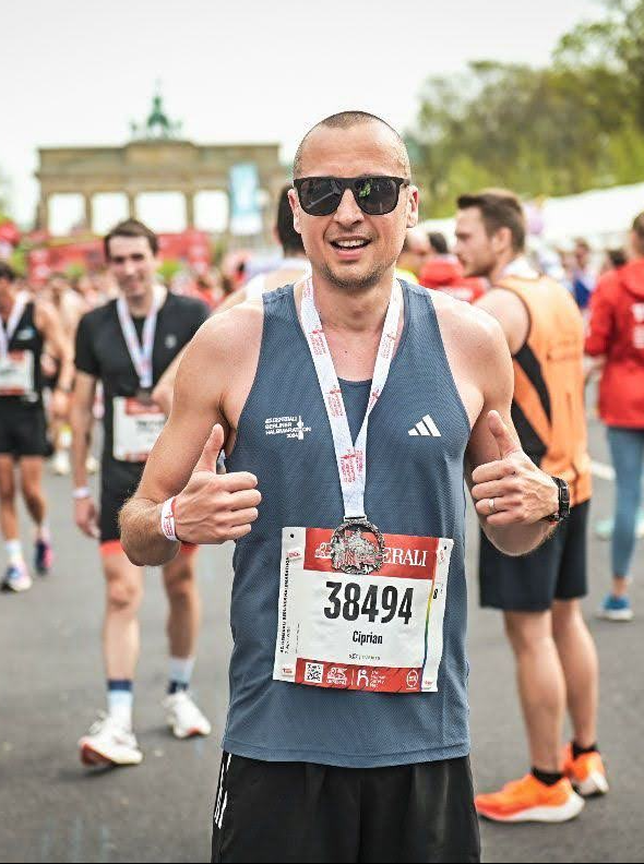 Ciprian Ungureanu at the finish line of the Berlin Half Marathon 2024 with race number 38494, with the Brandenburg Gate in Berlin in the background.