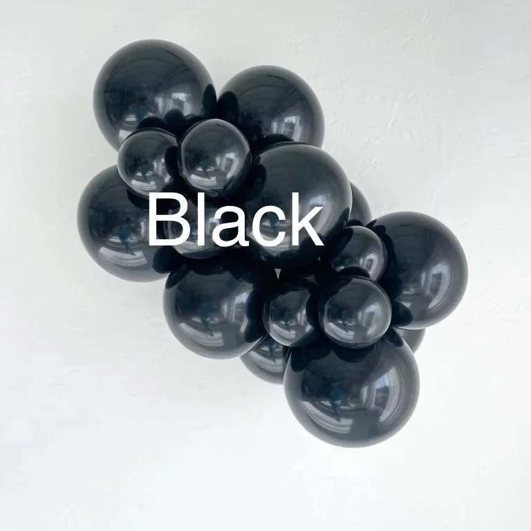 Cluster of glossy black balloons tied together, floating against a white ceiling.
