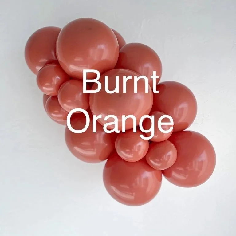 Cluster of burnt orange colored spherical objects, possibly balloons or spheres, arranged on a plain light background.