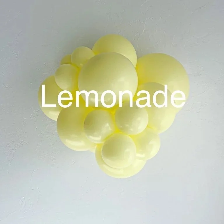 Cluster of yellow balloons attached to the ceiling with the word "Lemonade" overlaid in white text.