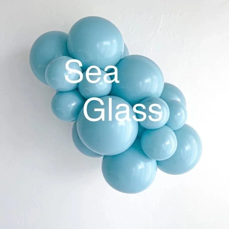 A sculpture made of clustered light blue glass spheres arranged in a cluster on a white wall with the words 'Sea Glass' overlayed.