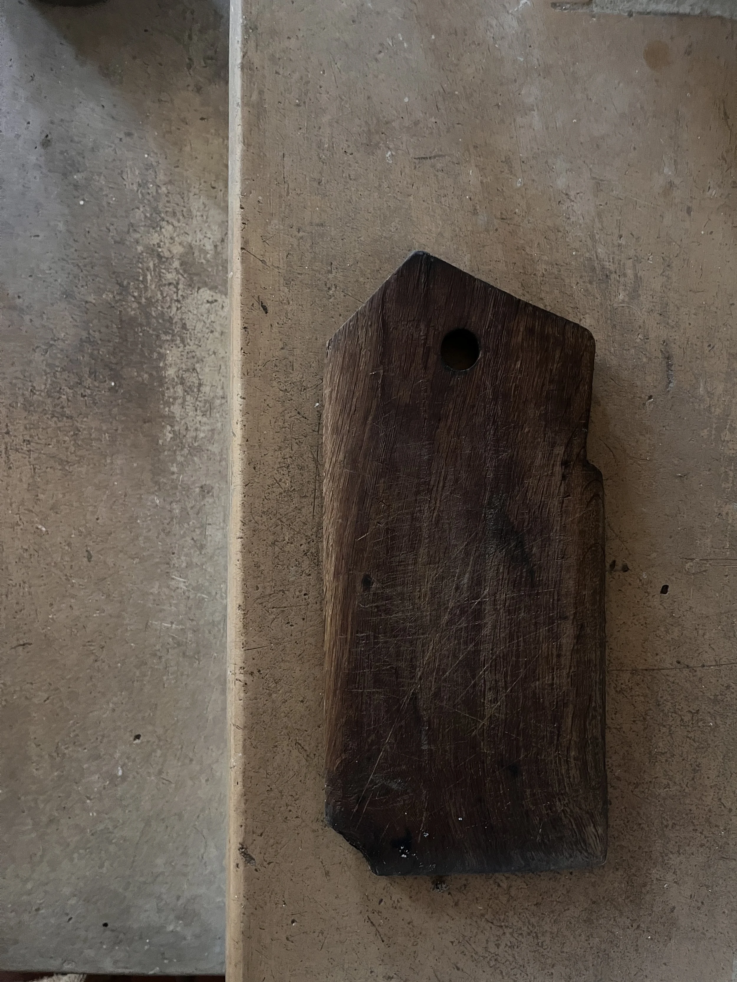 A piece of wood with a hole in it lying on a concrete floor.
