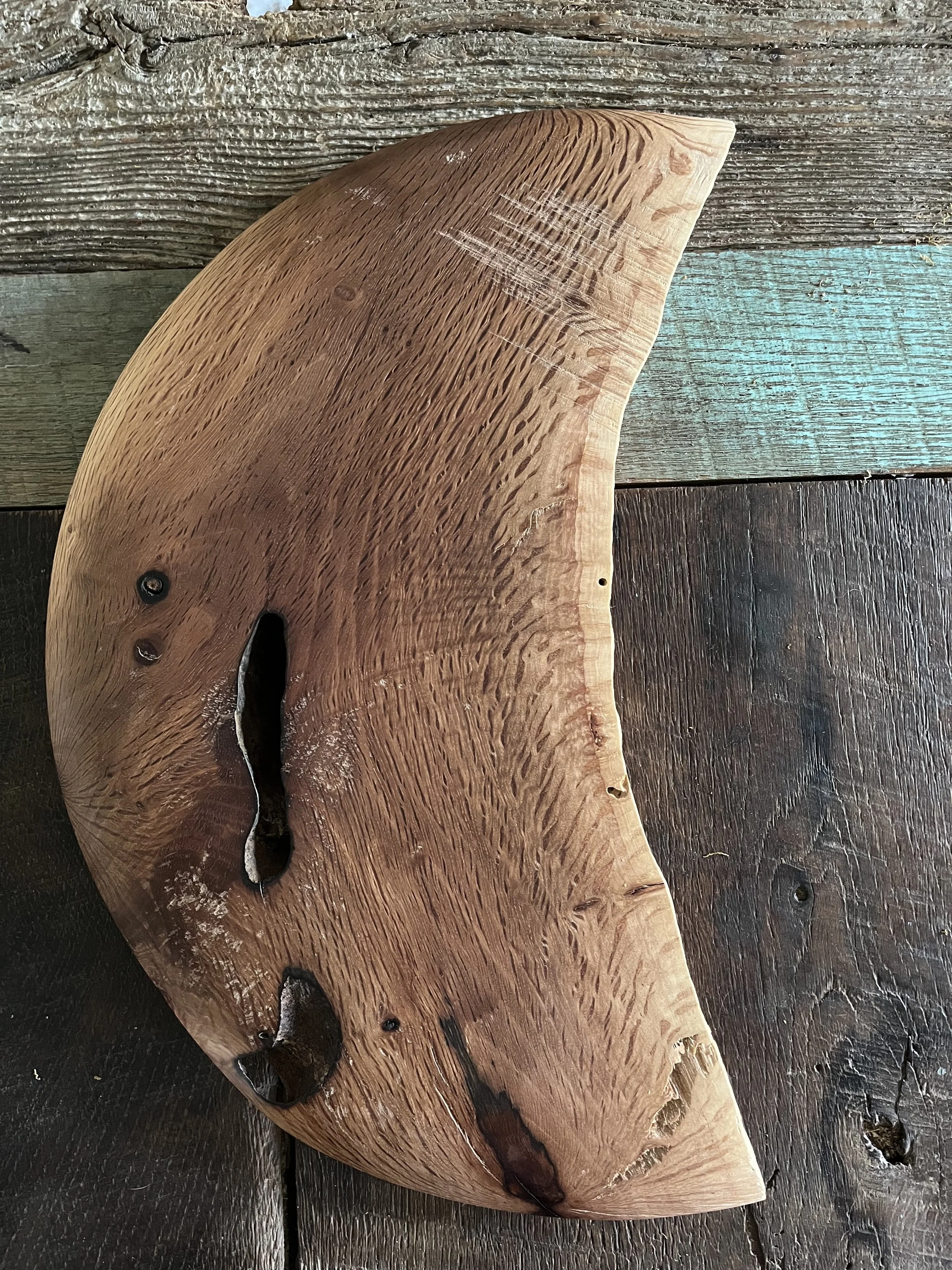 Smooth wooden slab with natural wood grain and irregular holes on a weathered wooden surface.