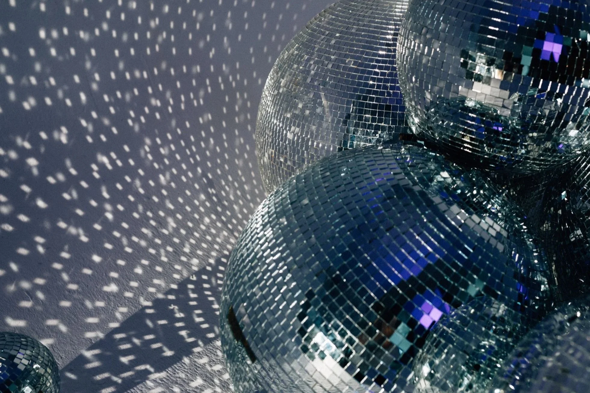A collection of disco balls reflecting light and casting dotted shadows on the wall.