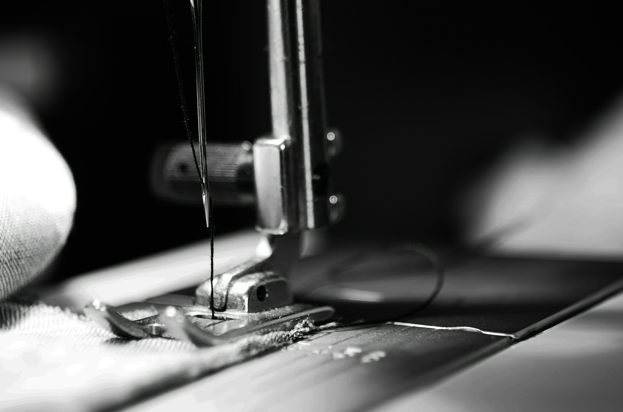 Close-up of a sewing machine needle and presser foot sewing fabric