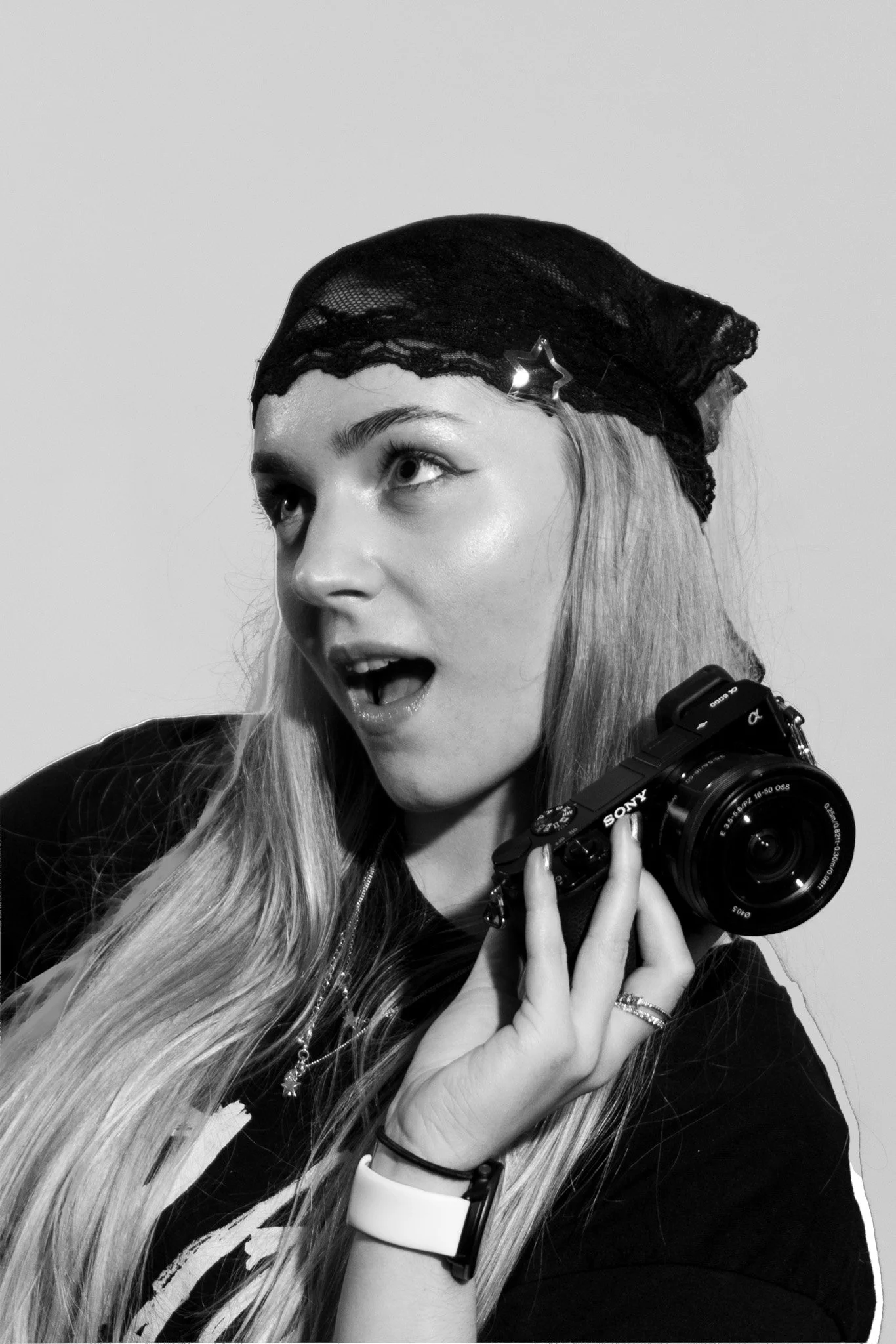 A young woman with long hair, wearing a black net cap with a star decoration, holding a Sony camera.