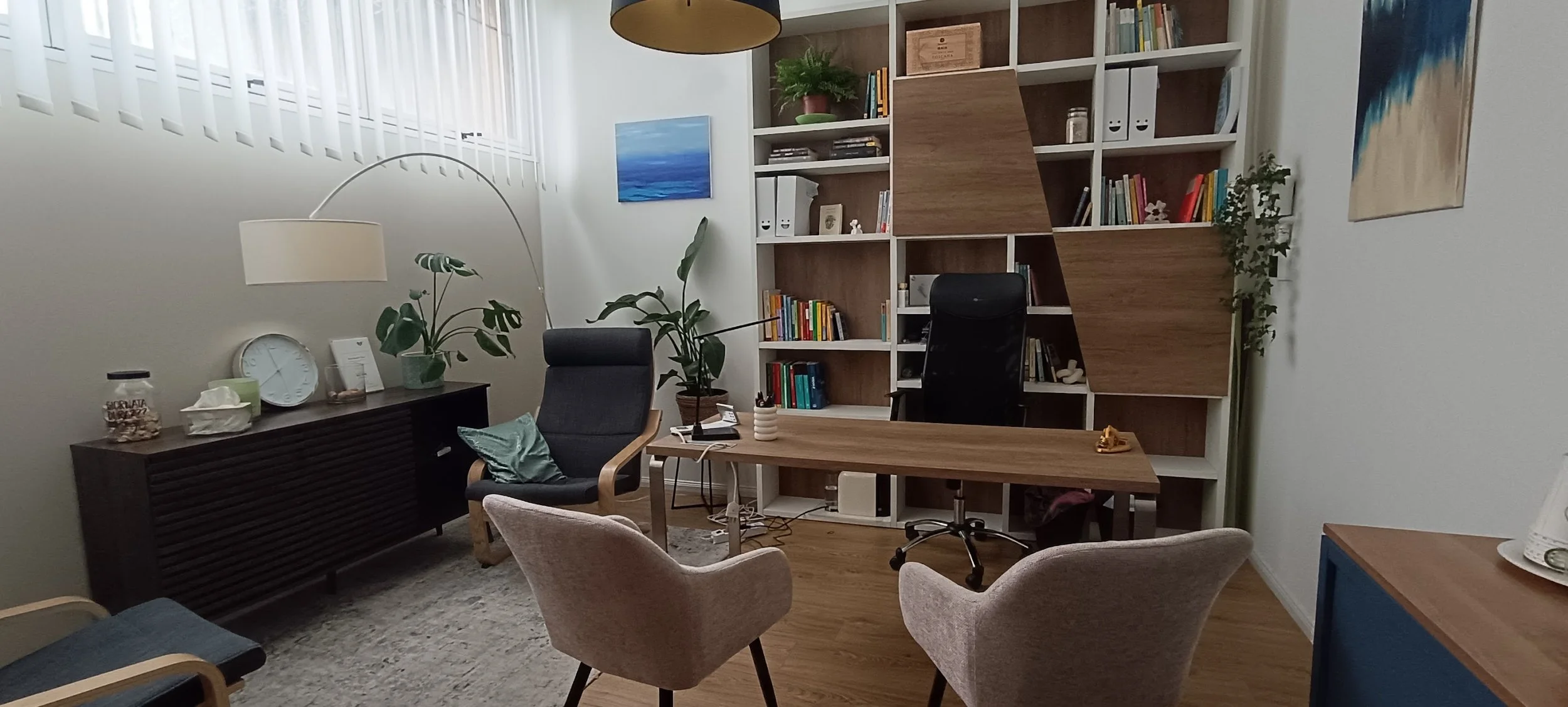 Ufficio con scaffale di legno, scrivania, sedie, piante e decorazioni, in stile moderno e accogliente.