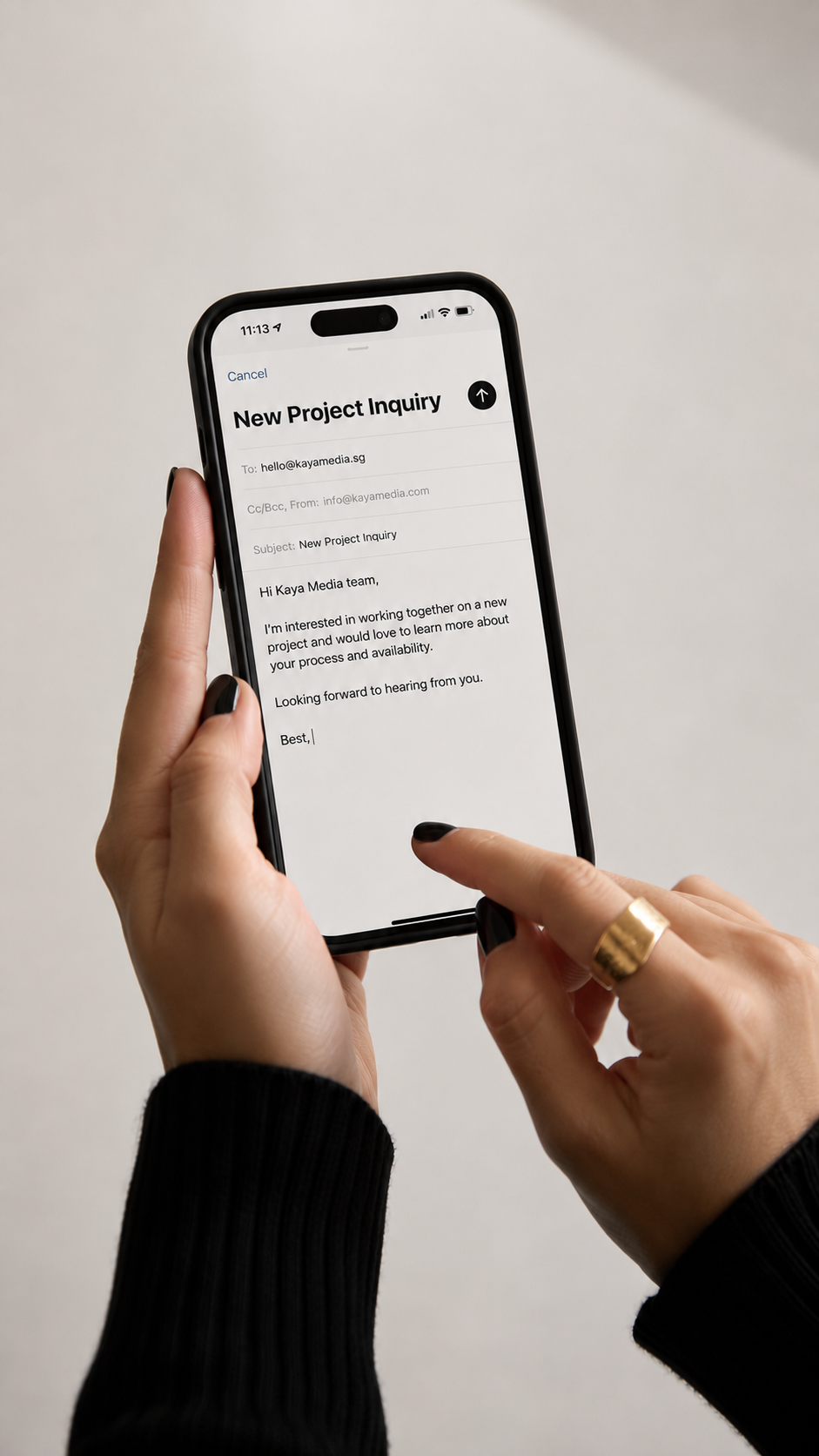 Social Media Manager holding a smartphone with an email draft titled 'New Project Inquiry' open on the screen, on a plain background.