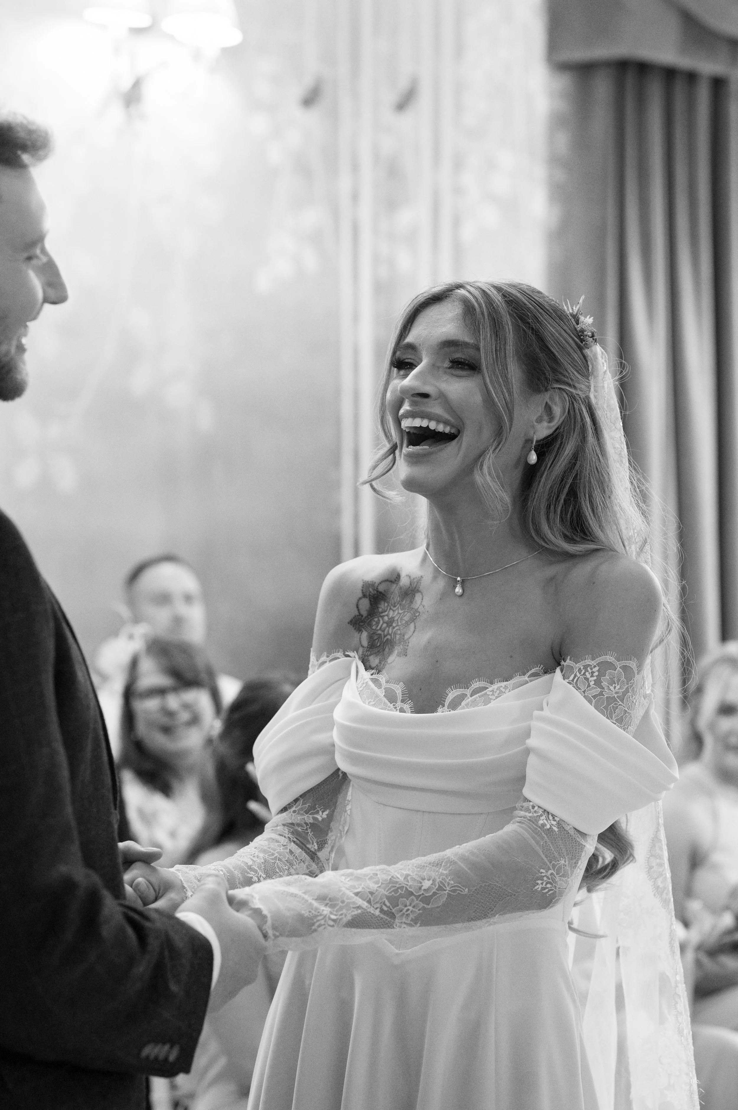 A bride and groom holding hands during their wedding ceremony, smiling at each other.