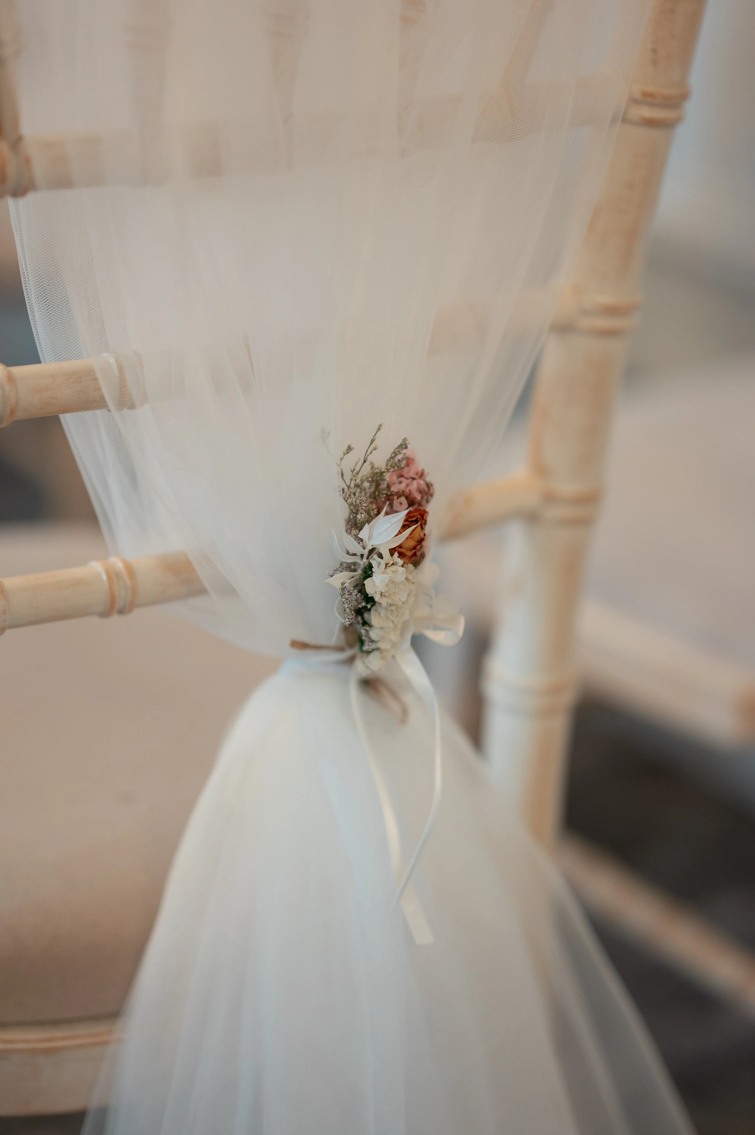 Close-up view of a chair decorated with a floral arrangement with pink and white flowers attached to the backrest.